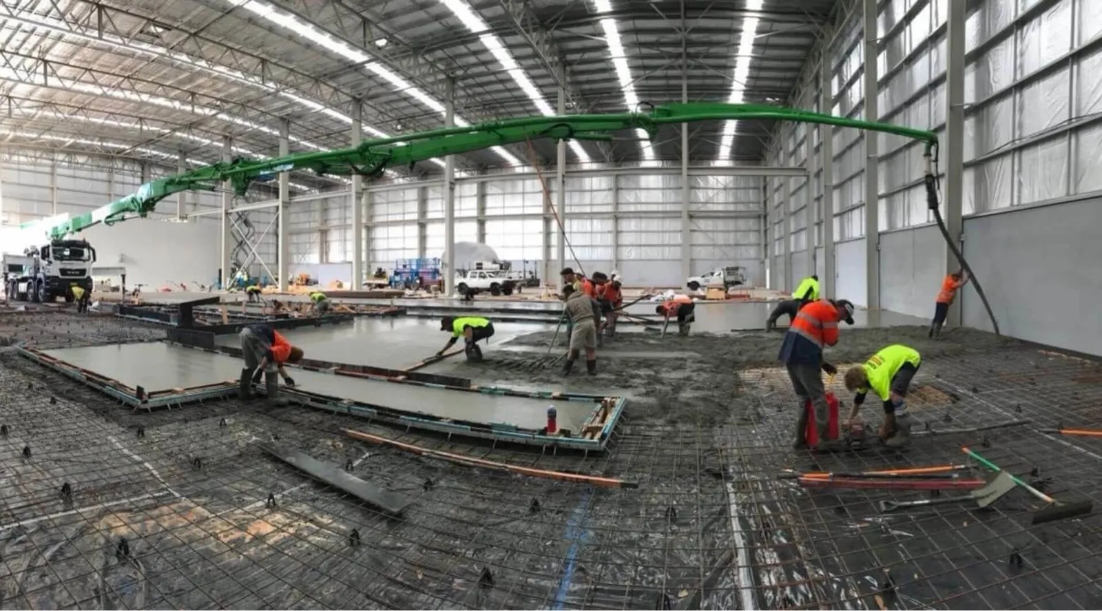 Concreters screeding a fresh slab fed by an HVCPS boom pump