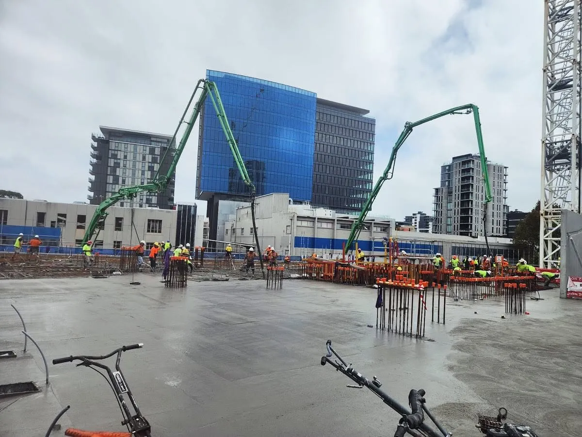 An HVCPS boom placing a commercial slab pour in front of a city tower