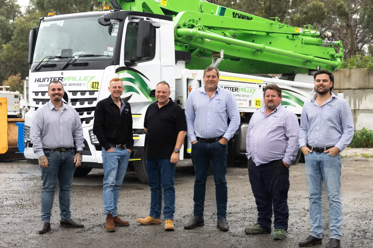 The HVCPS team standing in front of a Hunter Valley Concrete Pumping Service Schwing boom pump